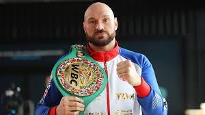 man proudly displays a boxing belt in front of him, showcasing his achievement in the sport.