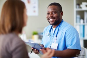 Smiling African doctor working with patient in his office