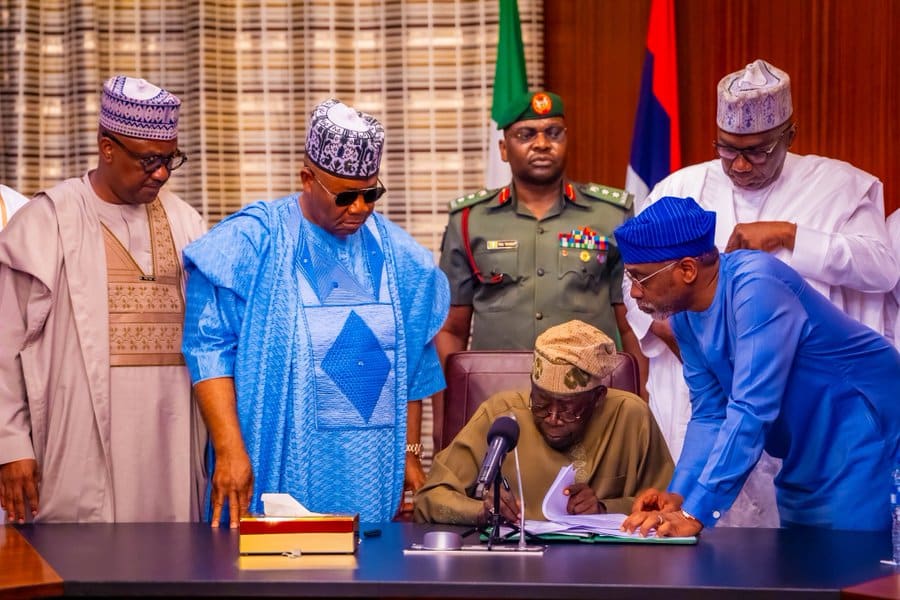 President Bola Tinubu signing the bills into law in the presence of Godswill Akpabio and others