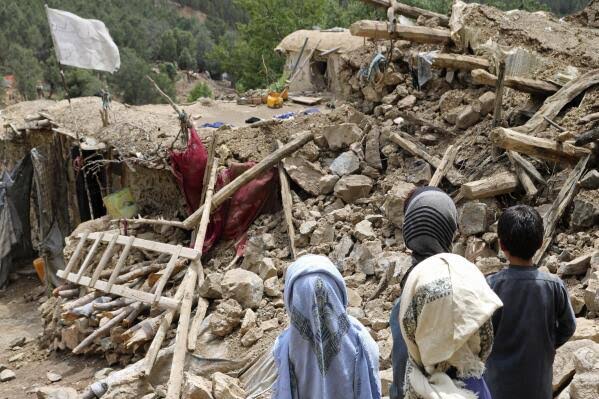 Afghan children stand near a house that was destroyed in an earthquake in June 2022 (AP News)